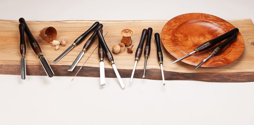 A range of woodturning tools and handmade wooden items displayed on a wooden backdrop