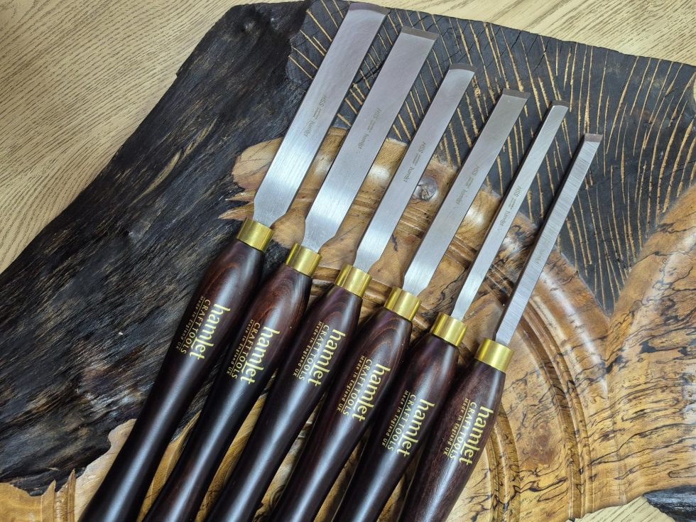 Range of six 'Hamlet' brand skew chisels laid on a wooden background